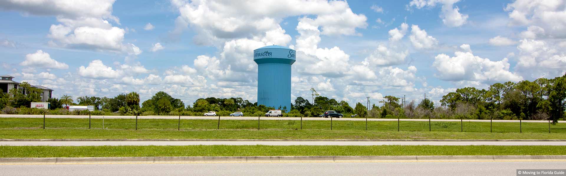 Tall blue water tower next to busy interstate